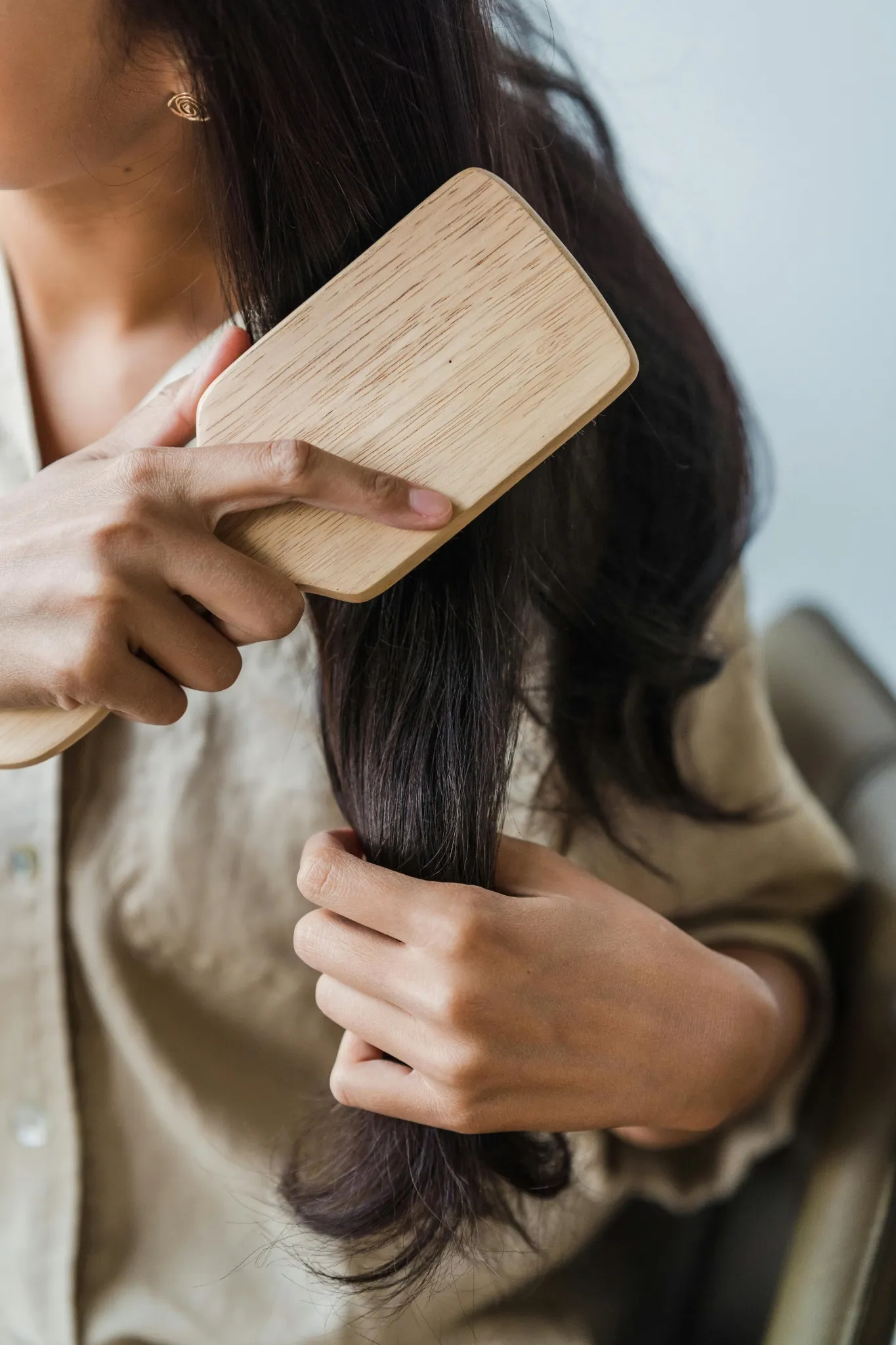 Woman brushing her long hair with a wooden comb | Shine Dermatology